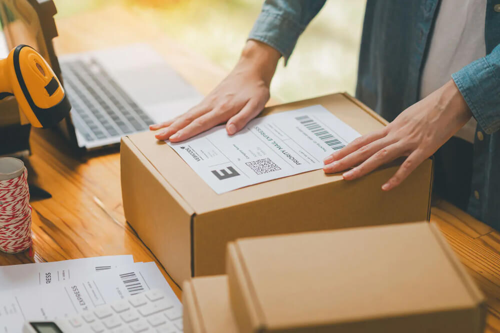 Eine Person klebt ein Versandetikett von Vebicode auf